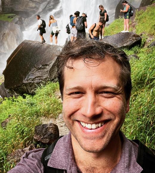 A photo of Evan Warfel in front of Lower Yosemite Falls